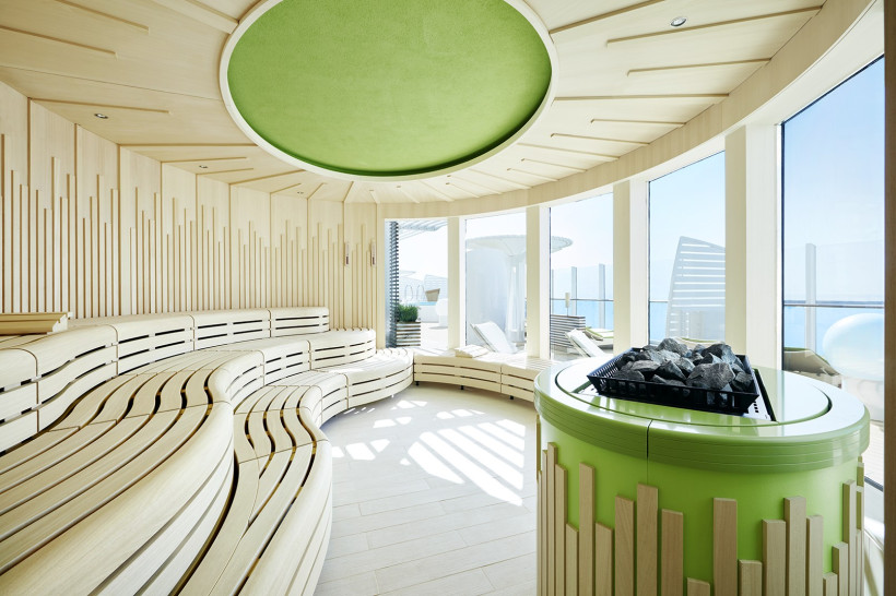 Finnische Sauna auf der AIDAprima mit gebogenen Holzliegen, Saunaofen und Panoramafenstern