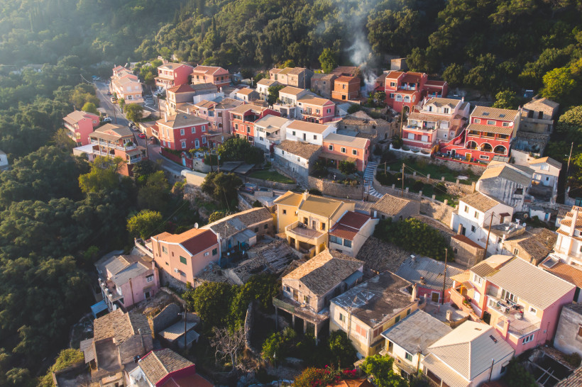 Wunderschöne Luftdrohnenansicht des Dorfes Lakones, traditionelles griechisches Dorf in der Nähe von Paleokastritsa, Insel Korfu, Kerkyra, Ionische Meeresinseln, Griechenland, an einem sonnigen Sommertag mit blauem Himmel und Bergen