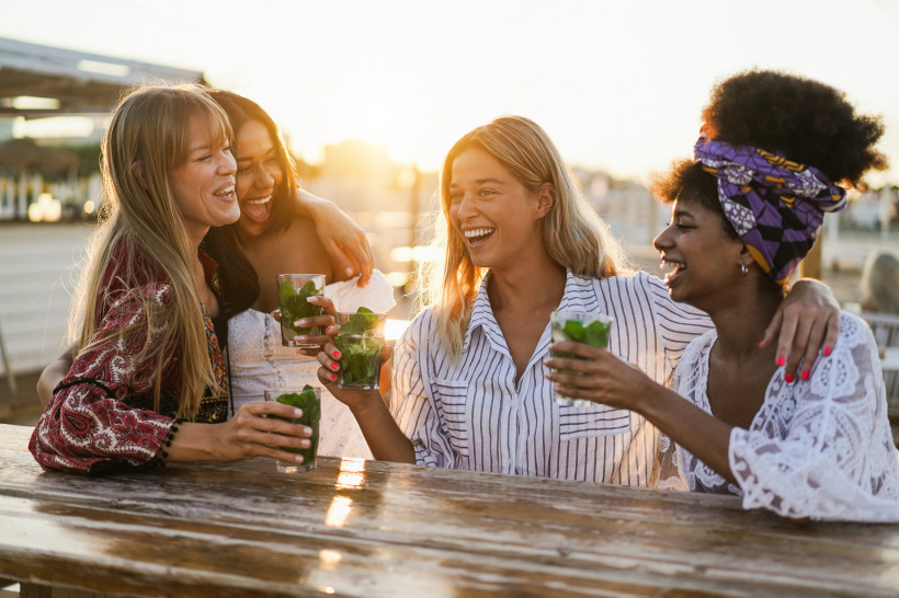 Freundesgruppe mit Getränken an einer Strandbar bei Sonnenuntergang in Playa d'en Bossa