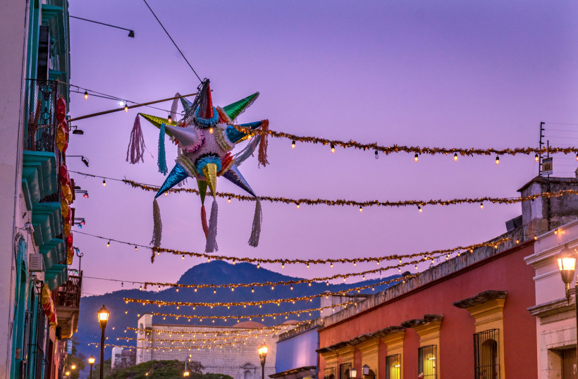 Weihnachten in Mexiko Bunte Weihnachts-Piñata in einer festlich geschmückten Straße mit Girlanden und Lichterketten bei Sonnenuntergang