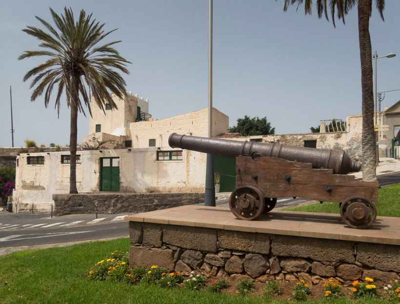 Casa Fuerte mit historischer Kanone im Vordergrund Historische Kanone auf Holzwagen vor dem Gebäude Casa Fuerte, mit Palmen im Hintergrund