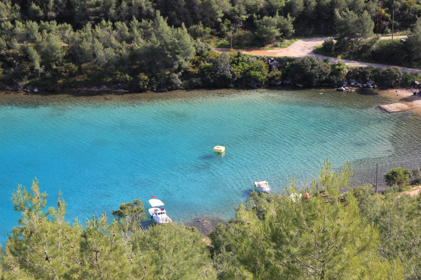 Ruhige Lagune mit kristallklarem Wasser, kleinen Booten und dichtem Pinienwald an der Küste