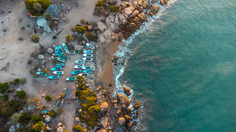 Arugam Bay, Sri Lanka Luftaufnahme von Fischerbooten und Felsen an der Küste von Arugam Bay in Sri Lanka mit türkisblauem Meer