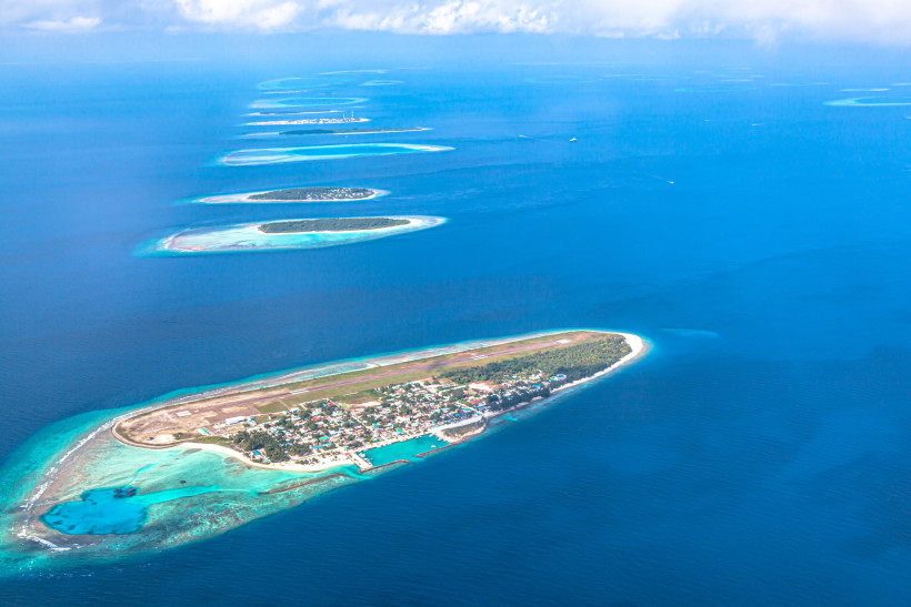 Luftaufnahme der Insel Dharavandhoo mit Landebahn, Siedlung und Lagune im Atoll