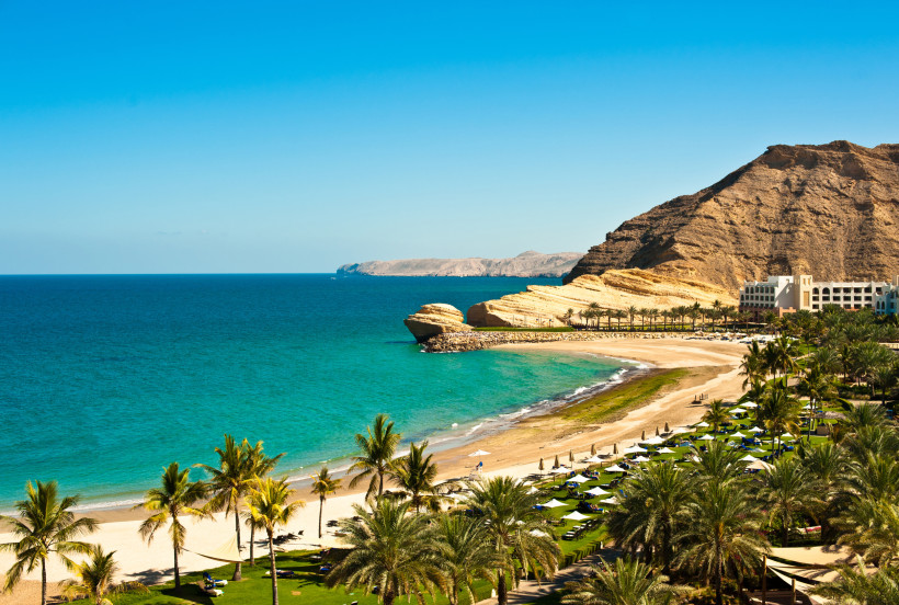 All Inclusive Resort in Oman am Sandstrand mit Palmen, türkisblauem Meer und beeindruckender Berglandschaft – luxuriöser Badeurlaub im Orient