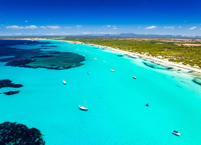Luftaufnahme der Bucht von Es Trenc auf Mallorca mit türkisfarbenem Meer, Sandstrand und Segelbooten