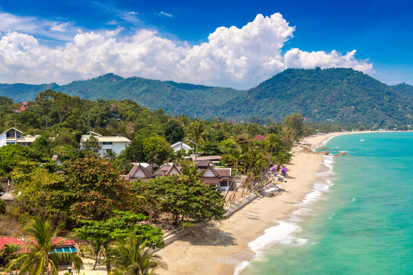Lamai Beach auf Koh Samui, Thailand: ruhiger Sandstrand mit türkisblauem Wasser, grünen Bergen und kleinen Resorts in tropischer Umgebung.