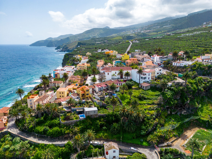 Küstenort auf La Palma mit bunten Häusern, Palmen und Steilküste am Atlantik