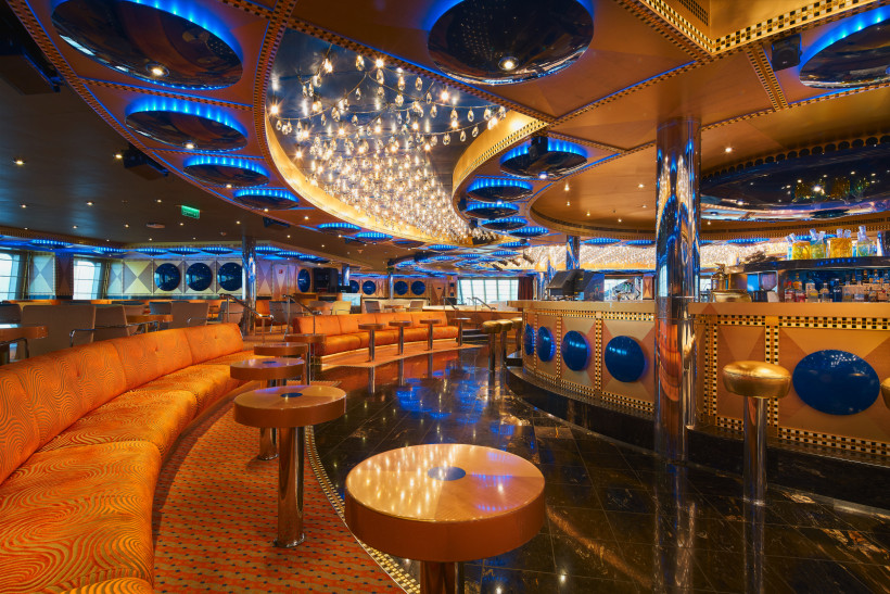 Costa Favolosa Lounge mit Bar, Sitzbereichen und dekorativer Deckenbeleuchtung Lounge auf der Costa Favolosa mit Barbereich, orangefarbenen Sitzbänken und blau beleuchteter Decke