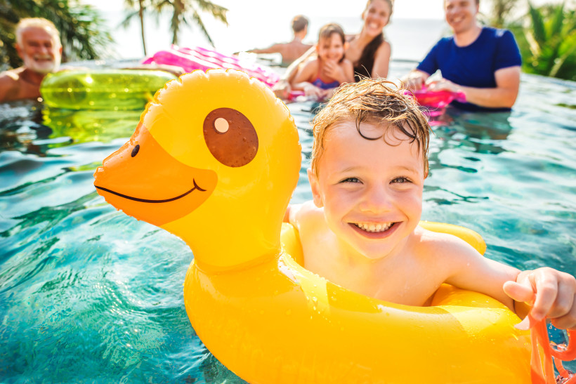Kind spielt im Pool mit Schwimmtier – Familienurlaub im Hotel mit kinderfreundlicher Poolanlage
