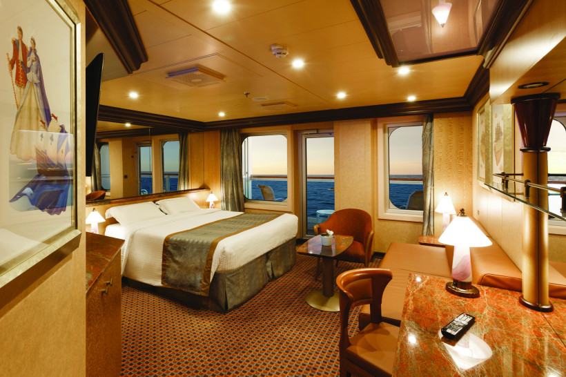 Costa Diadema Suite – Schlafzimmer mit Sitzbereich und Meerblick Suite auf der Costa Diadema mit Doppelbett, Sitzbereich und großen Fenstern mit Meerblick