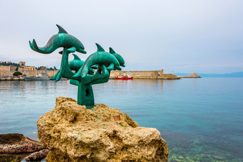 Skulptur im Hafen von Rhodos-Stadt mit Blick auf das Meer und die historische Altstadt – bekannte Sehenswürdigkeit auf Rhodos