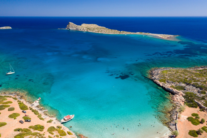 Luftaufnahme der Bucht am Kolokitha Beach bei Elounda mit türkisfarbenem Meer, Sandstrand und Felsenküste