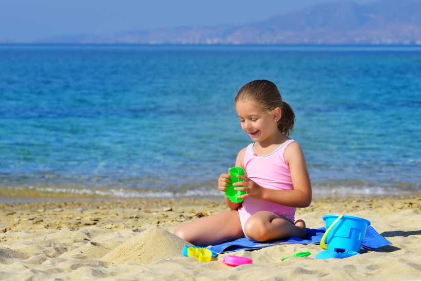 Kind spielt am Sandstrand mit Sandspielzeug, Meer im Hintergrund, Almyros Beach