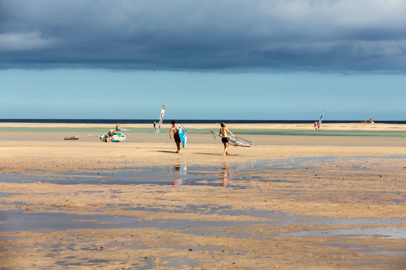 Strand von Costa Calma mit Wattflächen bei Ebbe und Windsurfern am Ufer