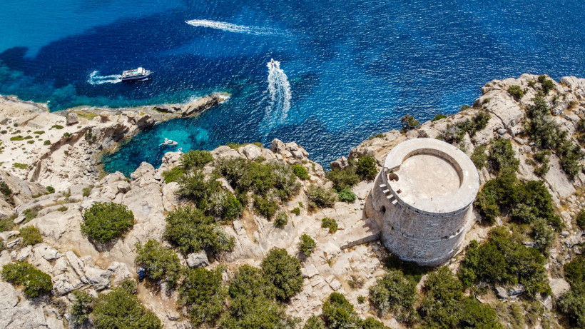 Torre des Savinar an der Küste, Luftaufnahme Torre des Savinar auf felsiger Küste über dem Meer, Luftaufnahme mit Booten im Wasser