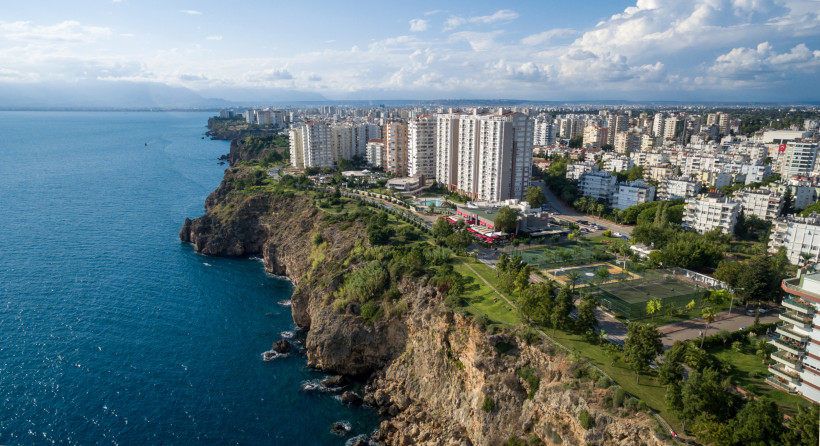 Blick auf Antalyas markante Felsenküste mit Wohngebieten und tiefblauem Meer – charakteristisches Stadtbild im Antalya Urlaub.