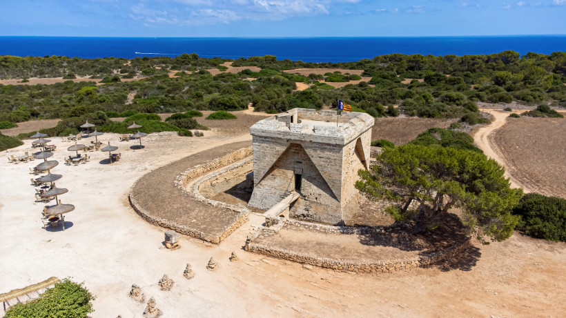 Wehrturm an der Punta de n’Amer mit umliegender Dünenlandschaft und Blick auf das Meer