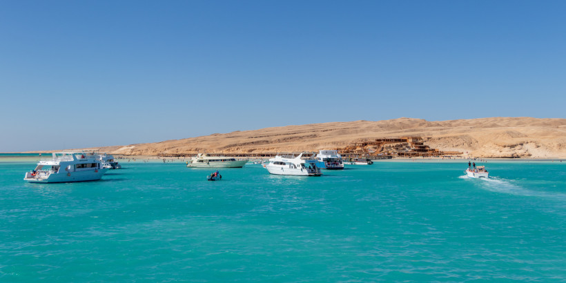 Insel-Ausflug im Roten Meer – traumhafte Bootstour in Ägypten genießen Ausflugsschiffe vor einer sonnigen Küste mit türkisblauem Wasser und Wüstenlandschaft
