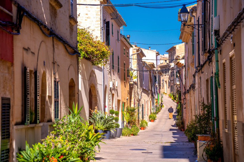 Schmale Gasse in der Altstadt von Alcúdia mit Natursteinfassaden und traditionellen Häusern