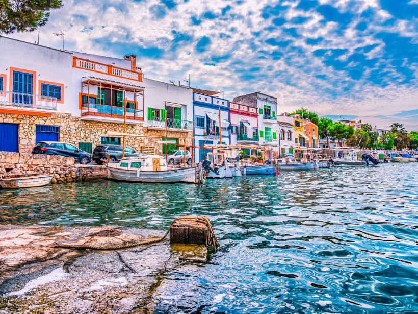 Hafenpromenade in Cas Antic in der Altstadt mit bunten Häuserfassaden und kleinen Booten am Kai
