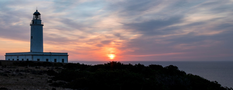 Formentera - Faro de Cap de Barbaria Leuchtturm Faro de Cap de Barbaria auf Formentera vor einem farbenprächtigen Sonnenuntergang. Links der weiße Turm, rechts die Sonne über dem Meer.