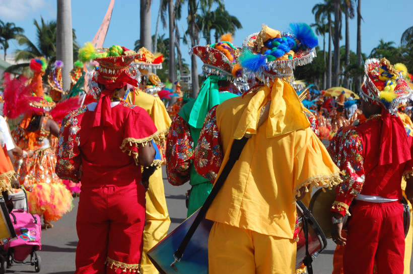 Carnival del Límon, Costa Rica Menschen in bunten traditionellen Karnevalskostümen nehmen an einer Straßenparade teil, umgeben von Palmen und Sonnenschein