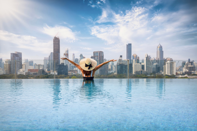 Luxushotel in Bangkok – Rooftop-Infinity-Pool mit Skyline-Blick Frau entspannt in einem Rooftop-Infinity-Pool mit Blick auf die Skyline von Bangkok – ein luxuriöses Hotelerlebnis im Herzen Thailands.