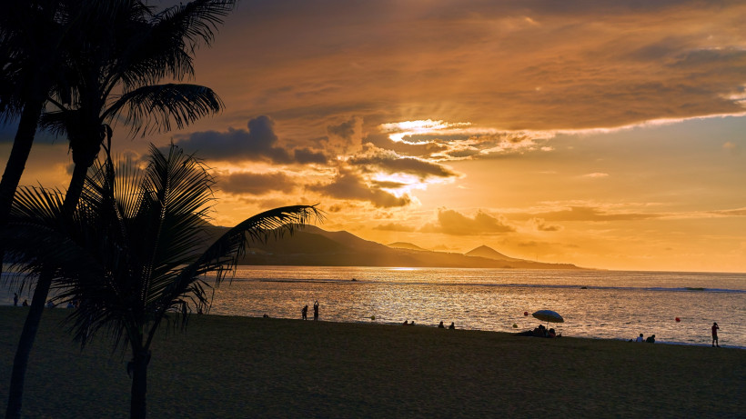 Sonnenuntergang über der Playa de las Canteras auf Gran Canaria mit Palmensilhouette, Strand und Meer