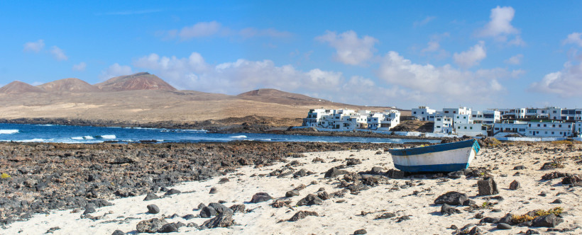 Küste von La Santa – Vulkanlandschaft und traditionelles Fischerörtchen auf Lanzarote Blick auf La Santa an der Westküste Lanzarotes mit heller Vulkanlandschaft, weißen Häusern und felsiger Küste.