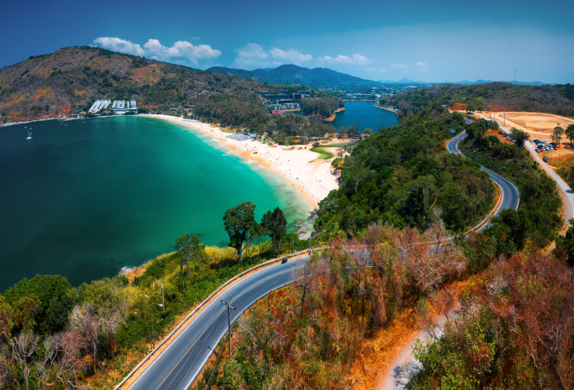 Panoramablick auf den Nai Harn Beach mit türkisfarbener Bucht, Sandstrand und bewaldeten Hügeln