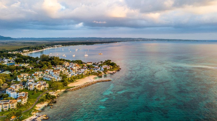 Negril Küste Jamaika – Karibikparadies von oben Luftaufnahme der Küste von Negril, Jamaika mit Strand, türkisfarbenem Meer und Resorts bei Sonnenuntergang.