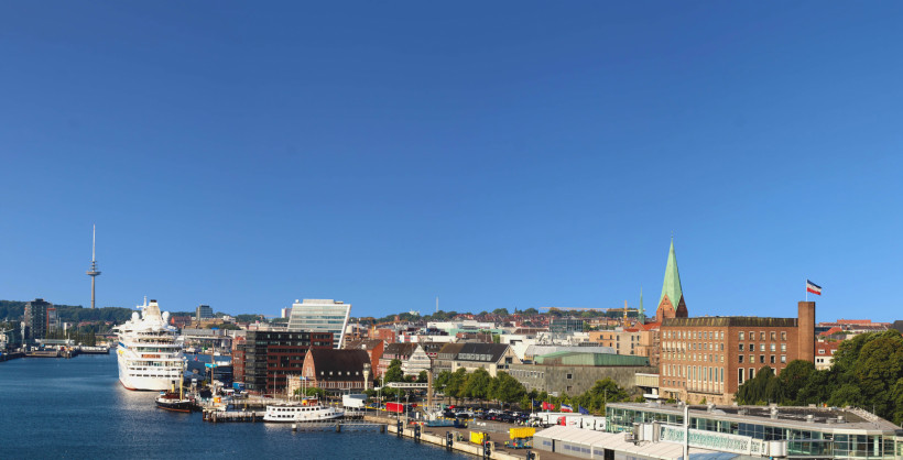 Kreuzfahrt ab Kiel: Hafenansicht mit Kreuzfahrtschiff und Stadtpanorama Kreuzfahrtschiff im Hafen von Kiel mit Stadtansicht und Kirchturm