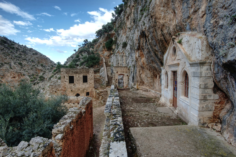 Santorini - Akrotiri  In eine Felswand gebautes Kloster mit kleiner Kapelle, Ruinenmauern und Treppenweg in einer Schlucht
