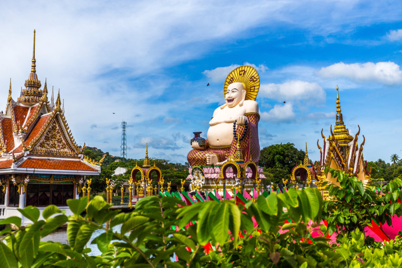 Lachender Buddha im Wat Plai Laem Tempel auf Koh Samui – spirituelles Highlight Farbenfrohe Statue des lachenden Buddhas im Wat Plai Laem Tempel auf Koh Samui, Thailand, umgeben von kunstvollen Tempelbauten und tropischer Natur.