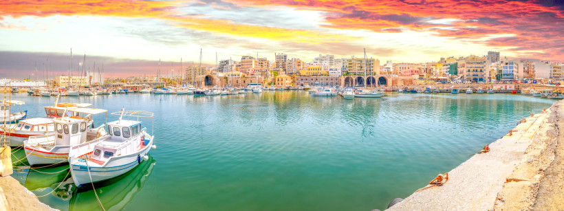 Hafen von Heraklion mit Segelbooten und Stadtbebauung am Ufer bei Abendlicht