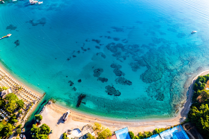 Moonlight Beach in Kemer mit heller Sand-Kies-Küste, flach abfallendem Wasser und leuchtend türkisem Meer