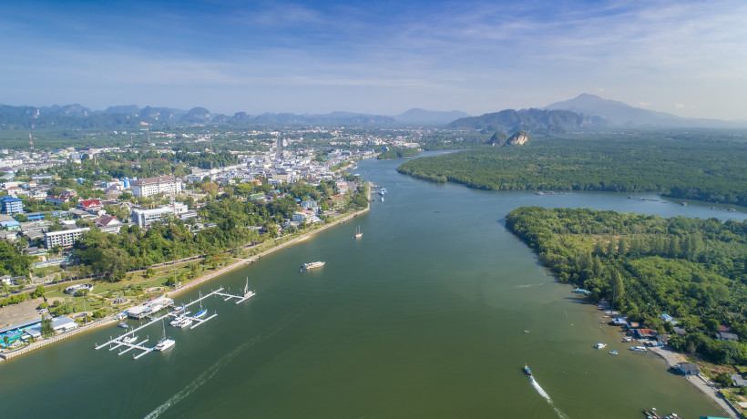 Luftaufnahme von Krabi Town mit Fluss, Hafen, grüner Landschaft und Bergen im Hintergrund in Südthailand.