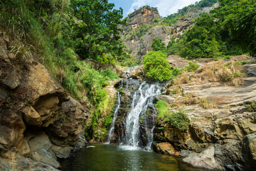 Ella, Sri Lanka Natürlicher Wasserfall in der Bergregion bei Ella, Sri Lanka, umgeben von Felsen und grüner Vegetation.