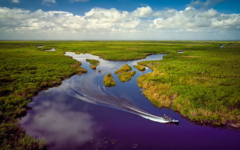 Everglades bei Miami: Wasserwege durch die Sumpflandschaft Sumpflandschaft der Everglades bei Miami mit Wasserkanal und Motorboot