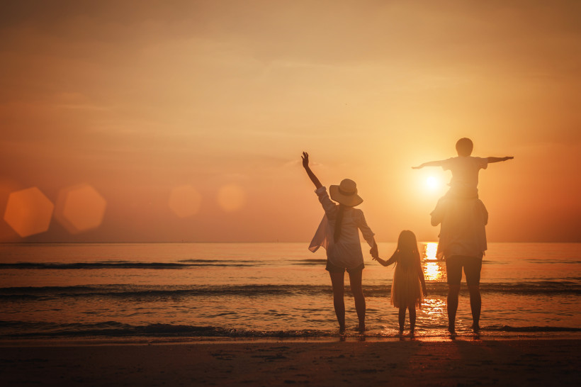 Familienurlaub am Meer – unvergessliche Momente bei Sonnenuntergang Familie steht am Strand und genießt einen warmen Sonnenuntergang am Meer. Eltern und Kinder halten Händchen, blicken auf das ruhige Wasser und erleben einen harmonischen Moment während ihres Familienurlaubs.
