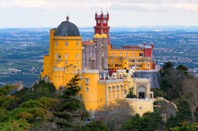 Palácio Nacional da Pena in Sintra, Portugal, mit gelben und roten Türmen auf einem bewaldeten Hügel