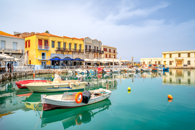Boote im venezianischen Hafen von Rethymno vor Uferpromenade mit bunten Gebäuden und Cafés