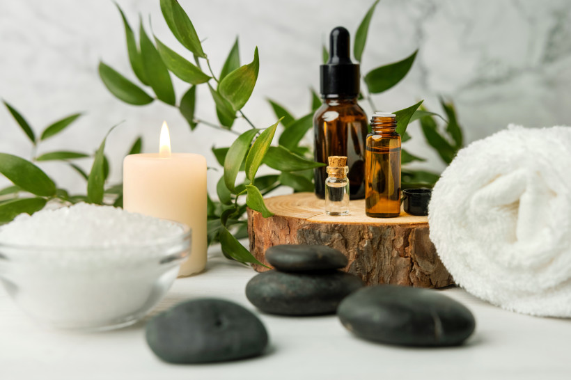 Wellness-Accessoires mit ätherischen Ölen, Kerze, schwarzen Steinen und Handtuch – natürliche Spa-Dekoration