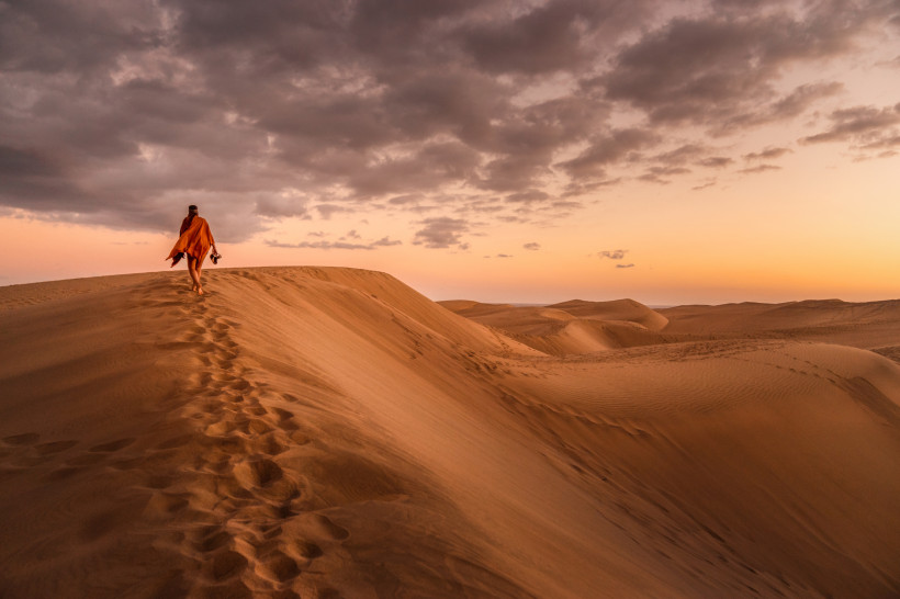 Sonnenuntergang in den Dünen von Maspalomas auf Gran Canaria Sanddünen von Maspalomas bei Sonnenuntergang mit einer Person auf einem Dünenkamm