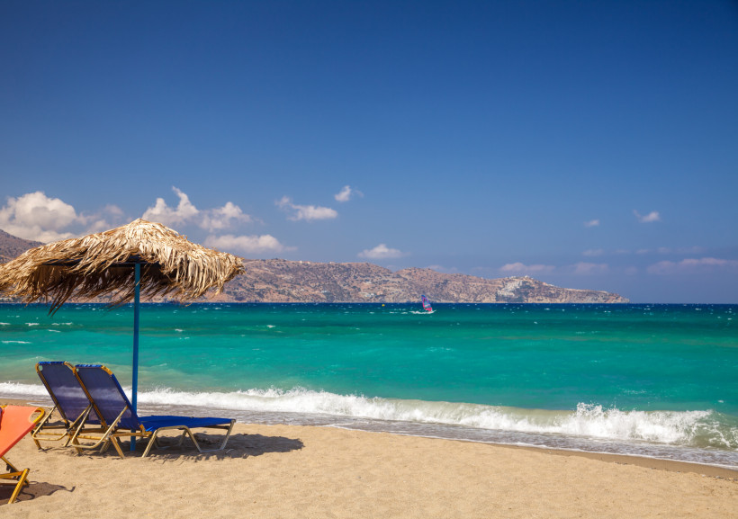 Kreta Strand mit Sonnenliegen und Blick auf die Berge