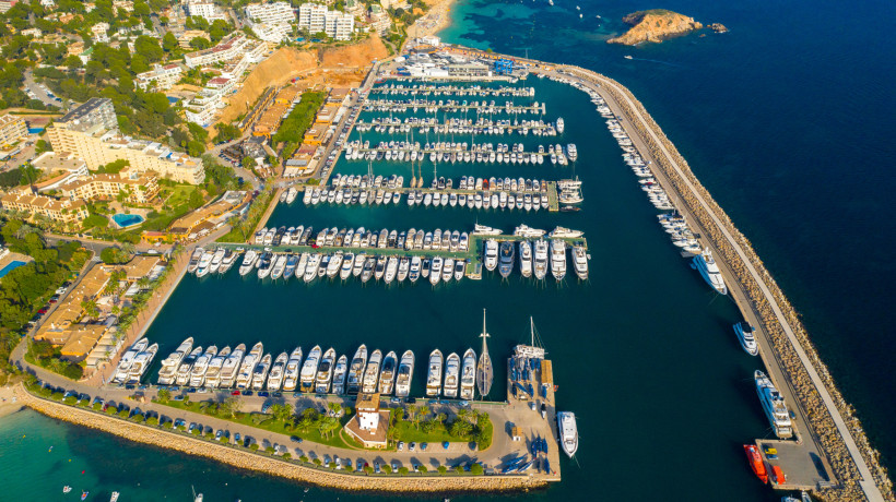 Luftaufnahme des Yachthafens Puerto Portals mit zahlreichen Booten an Stegen und einer langen Hafenmole