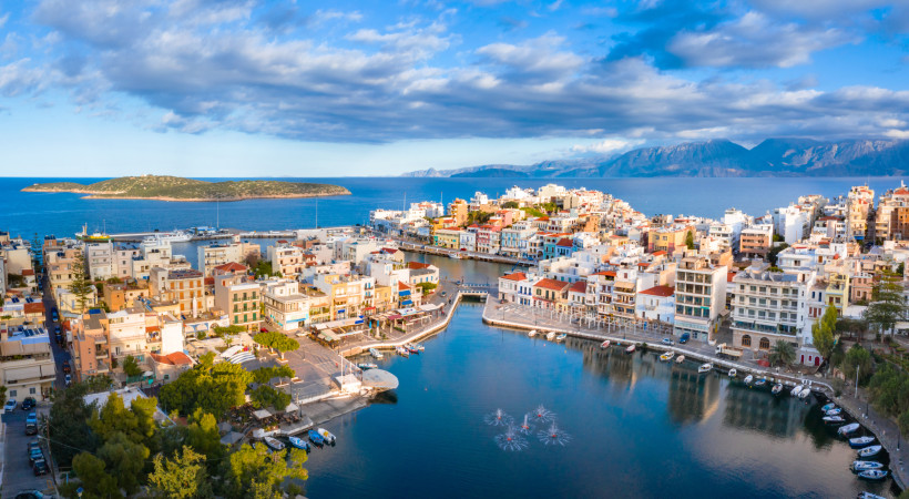 Hafen von Agios Nikolaos mit Uferpromenade und Booten Blick auf den Hafen von Agios Nikolaos mit Uferpromenade, Booten und Küstenstadt am Meer