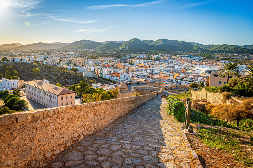 Ibiza-Stadt Steinerner Weg auf der Festungsmauer Dalt Vila mit weitem Blick über Ibiza-Stadt bis zu grünen Hügeln im Abendlicht.