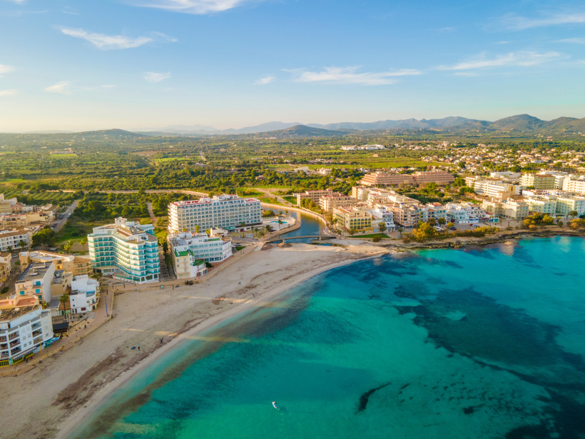 Luftaufnahme von S’Illot mit Strand, Küstenpromenade und türkisfarbenem Meer